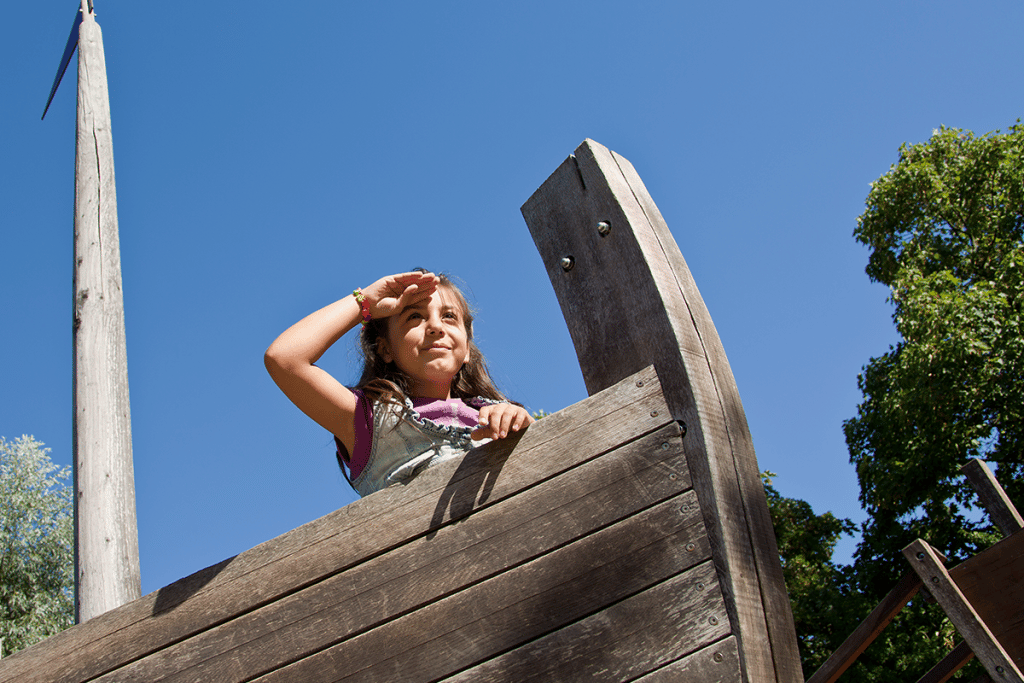 Ein Mädchen hält Ausschau auf dem Piratenschiff des Abenteuerspielplatzes.