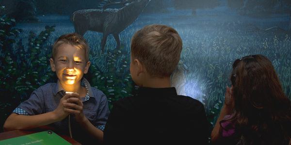 Drei Kinder entdecken den Nachtraum und benutzen die Taschenlampe, um die Stimmen von den Tieren der Nacht zu hören.